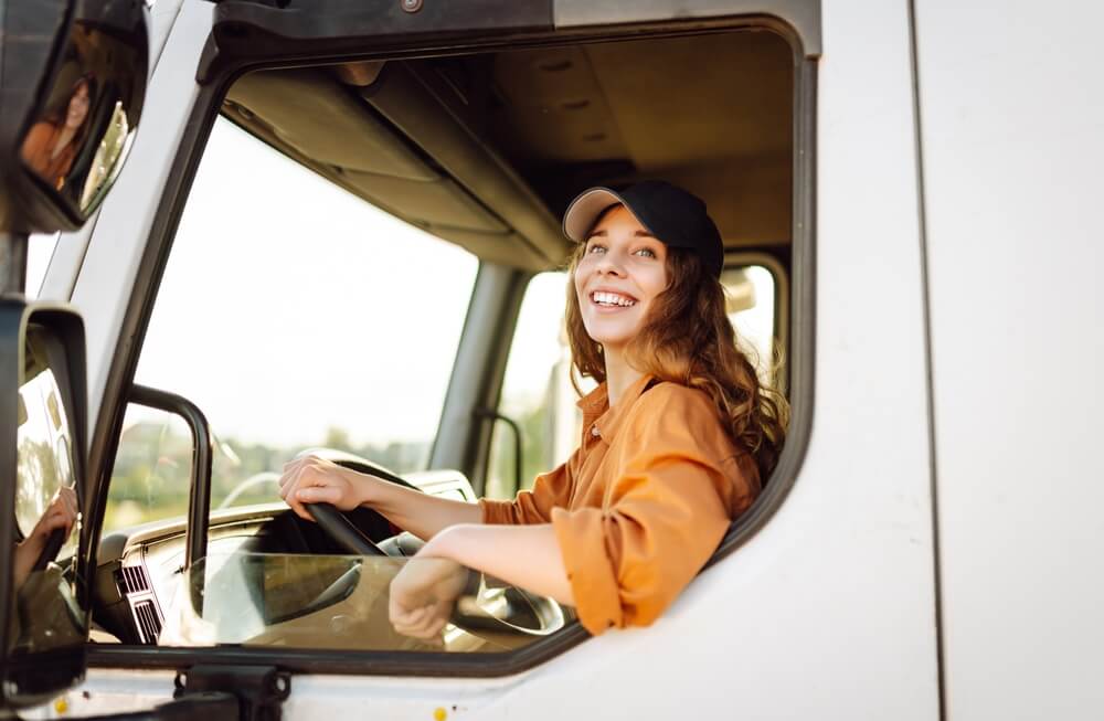 Smiling female truck driver looks out the window - best commercial auto insurance.