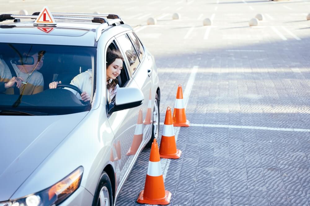 Student driver practicing around traffic cones to learn if driving school can lower car insurance.