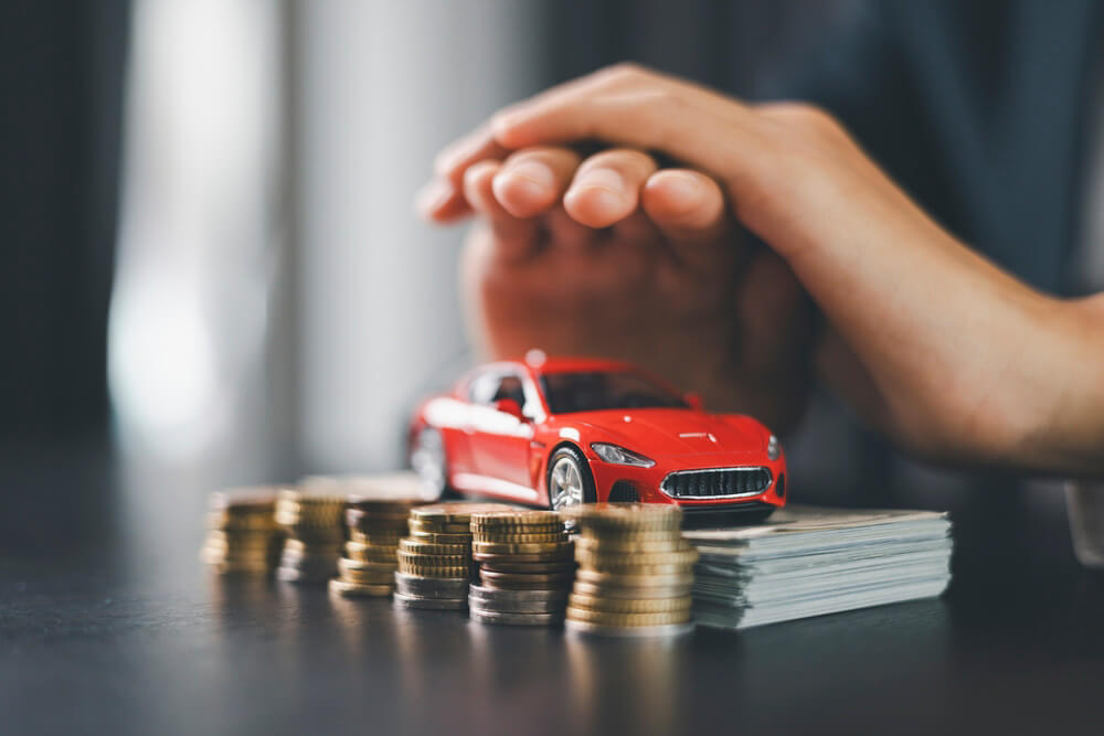 Model car with money and coins illustrating how driving school can lower car insurance costs.