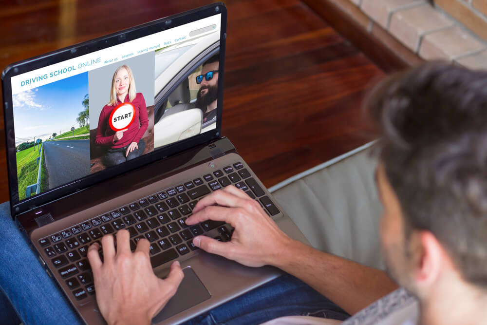 ino-does-driving-school-help-lower-car-insurance-premiums-1 Male sits on couch at home and takes an online driver's course, driver's safety course and lowering insurance rates.