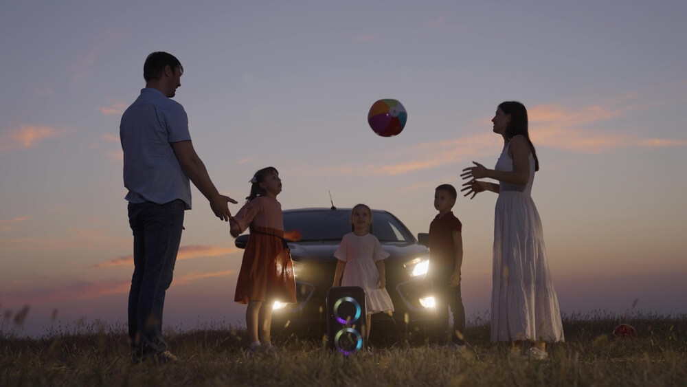Family plays ball in the sunset in front of their car, insurance with the right amount of car insurance,