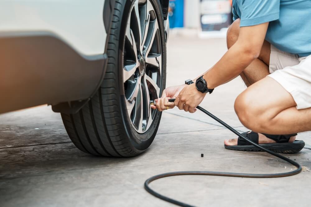 Man hand inflating tires of vehicle, removing tire valve nitrogen cap for checking air pressure and filling air on car wheel at gas station. Self service, maintenance and safety when driving on wet fall roads. Buying the best car insurance for protection.