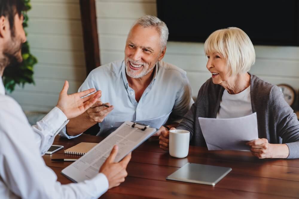 Happy mature family couple of clients consulting independent insurance agent about switching home insurance providers.