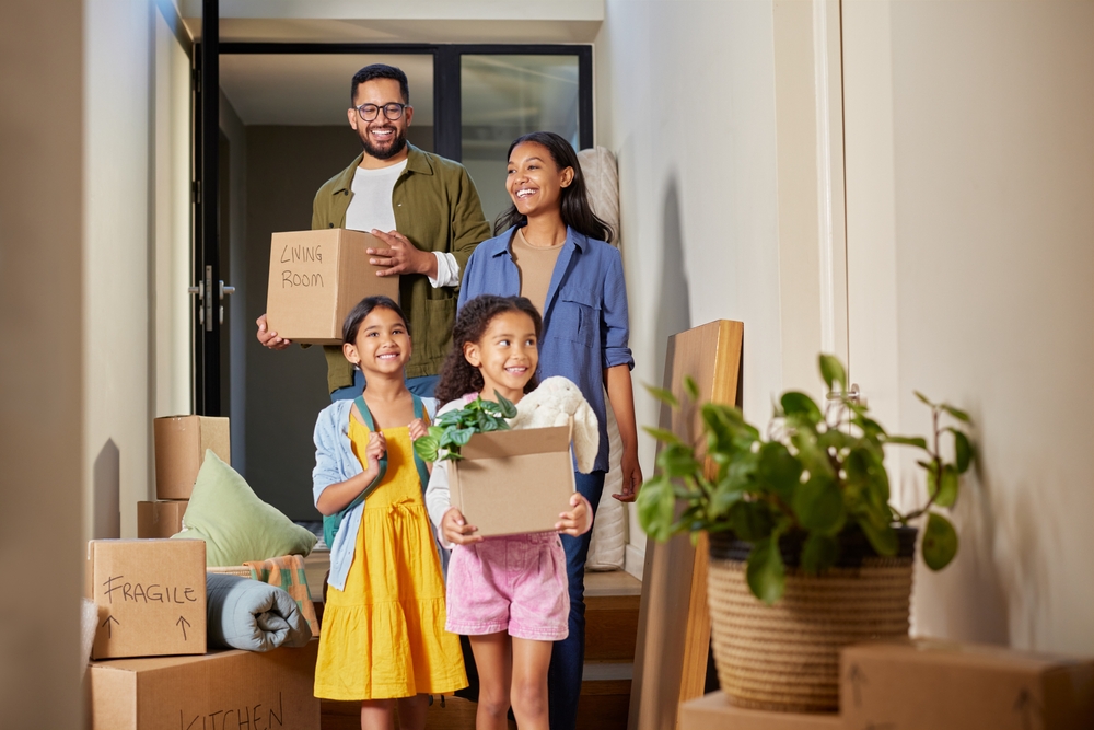 Happy family moving into their new home carrying their valuables making it important for them to have umbrella insurance to protect their important belongings.