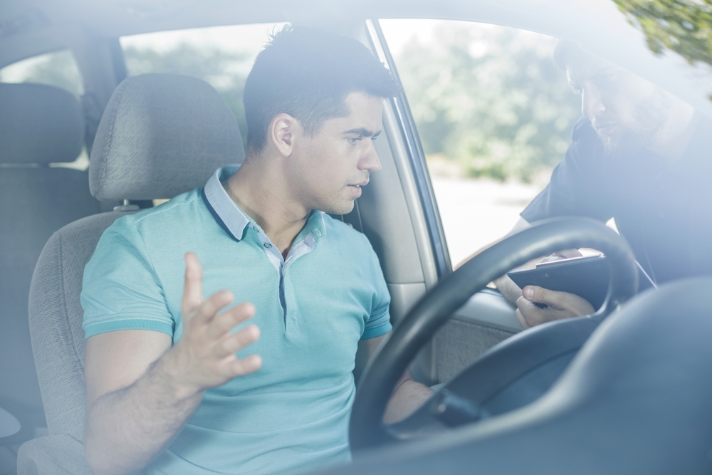 Guy getting pulled over for a speeding ticket while police officer asks for his car insurance information.
