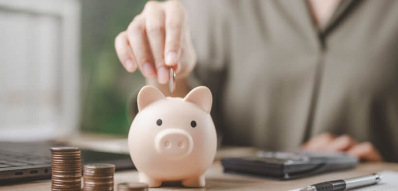 Woman adds a coin to a piggy bank, planning to save with multi-policy discounts.