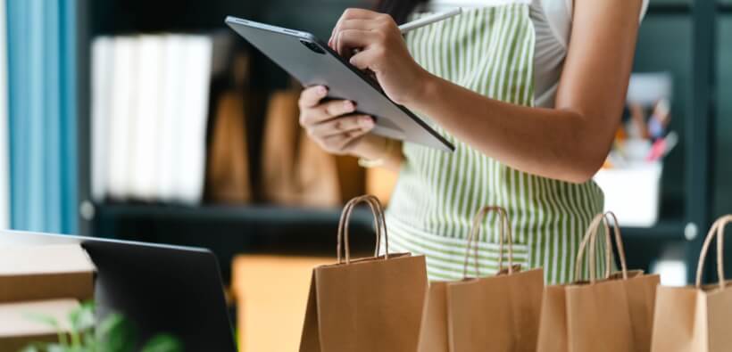 Small business owner using a tablet to manage orders and inventory, illustrating planning for business insurance growth as a company expands.