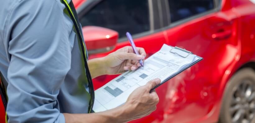 Insurance adjuster documenting vehicle damage after an accident with an uninsured driver, showing the steps to take when an uninsured driver hits you.