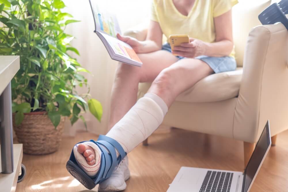 Remote worker recovering from a leg injury while working from home, highlighting business insurance needs such as liability coverage, business interruption, and protection for remote operations.