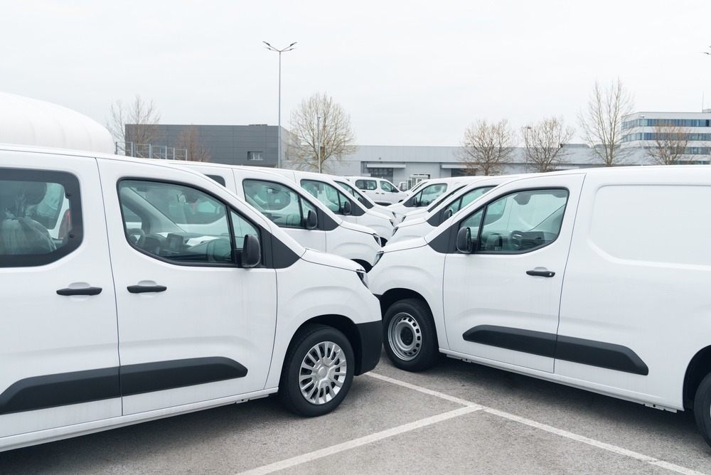 Fleet of commercial vans parked outside a business facility for company operations.
