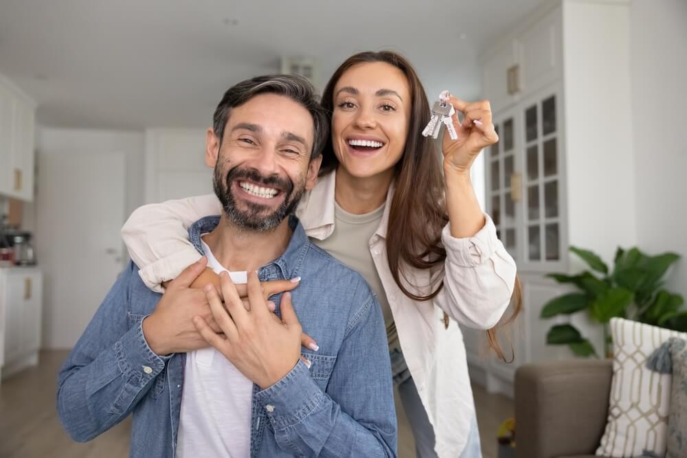 Propietarios de vivienda sosteniendo las llaves de su casa para representar ordinance and law coverage.