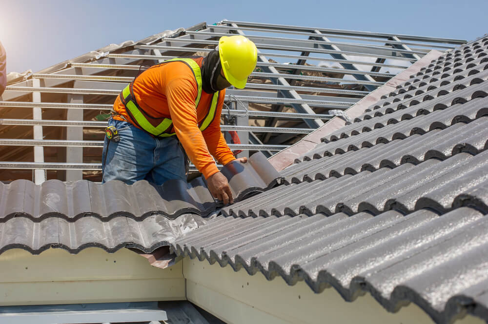 Roofing contractor installing new tiles for roof replacement coverage.
