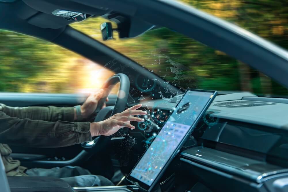 Driver uses a digital dashboard inside a smart car, showing how vehicle data, telematics and insurance can support modern driving insights.