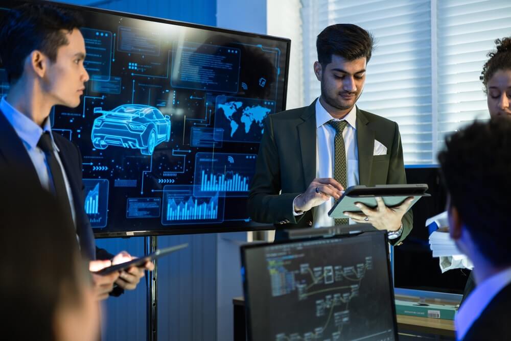 Business team reviews connected car analytics on digital screens, showing how vehicle data, telematics and insurance can work together.