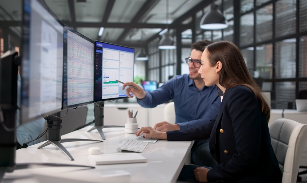 Payroll professionals reviewing data on multiple computer screens, representing multi-state payroll management.