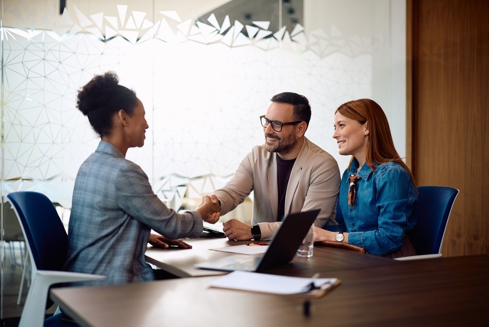 Insurance representative shaking hands with credit union members during a meeting to discuss more insurance choices.
