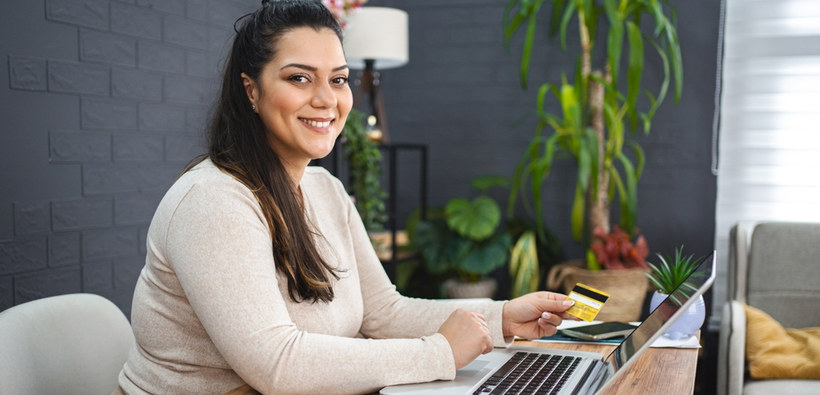 Woman using a laptop and holding a credit card, highlighting more insurance choices for credit union members.