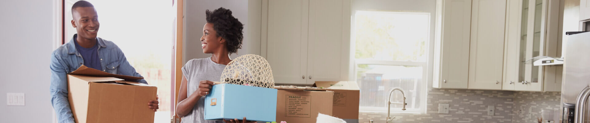 Happy young african american couple carrying boxes and moving into their rented apartment