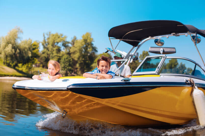 Father and kids cruising on a yellow boat with insurance