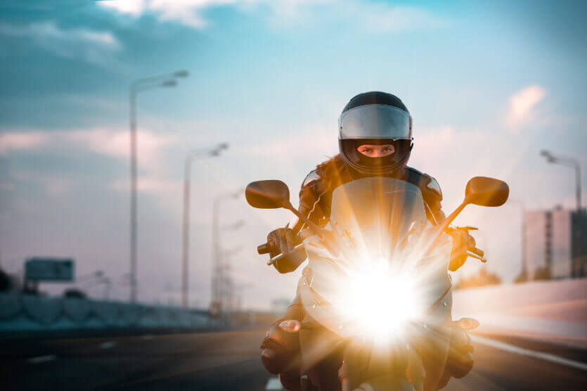 Front view of a motorcycle driver on highway with headlight on