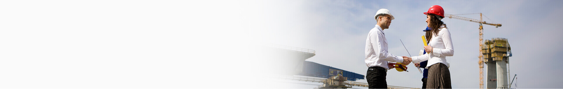Man and woman with safety helmets shaking hands at construction site