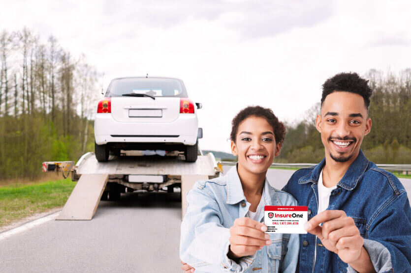 ima-motorcycle-lg-1-1 Smiling couple showing Insure One Road Assistance card as their car in the background is being towed away on the highway