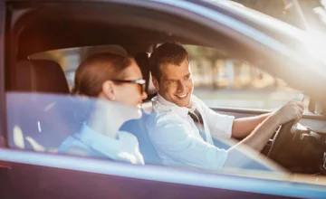 Man driving and laughing with a woman as co-driver.