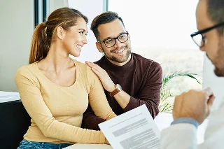 Insurance agent and young couple talking in office about adding collision coverage to their auto insurance policy.