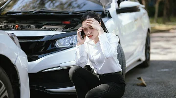 Asian woman calls insurance company for help after car accident.
