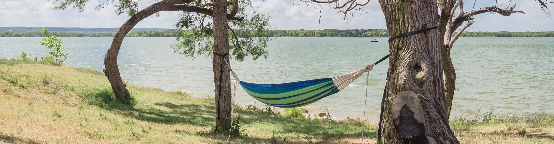 Empty green hammock in shade tree shades at lakeside park in Grand Prairie - best home insurance in Florida.