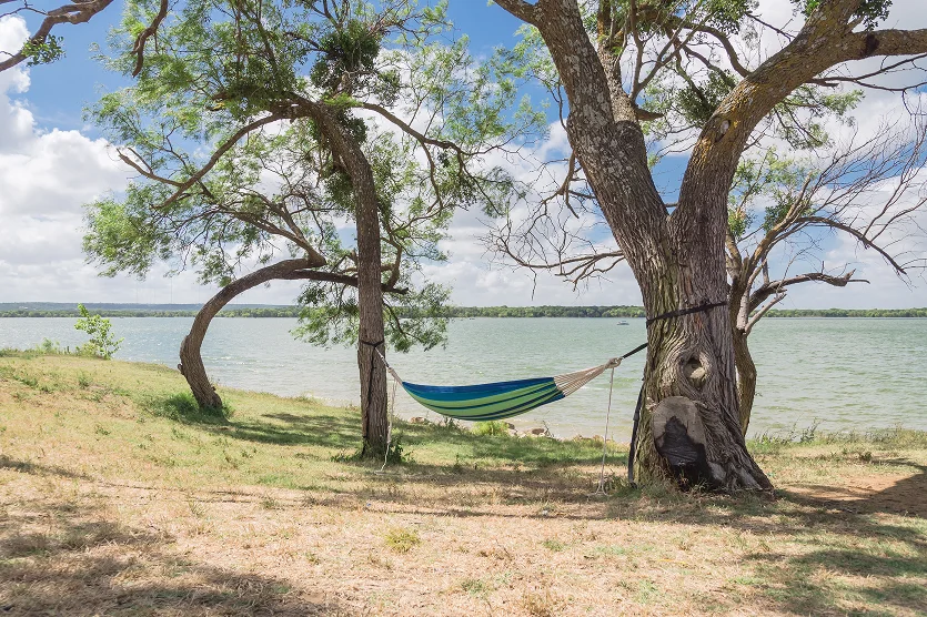 Empty green hammock in shade tree shades at lakeside park in Grand Prairie - best home insurance in Florida.