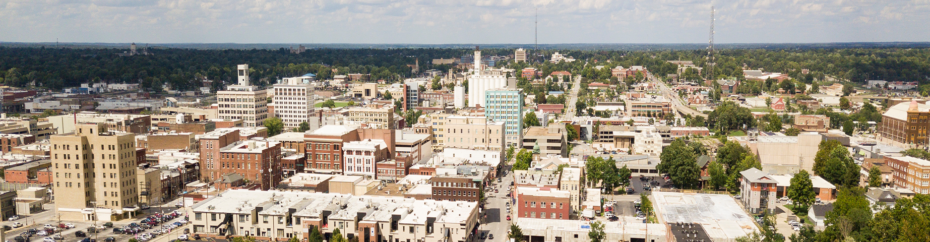 The downtown city skyline and buildings of Springfield MO under partly cloudy skies aerial perspective.