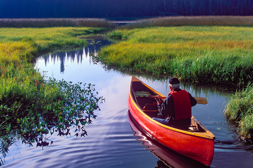 A man in a red canoe in Hosmer Lake in the Oregon Cascade mountains near Bend.