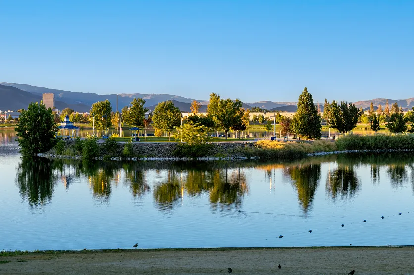 Sparks Marina Park during golden hour in late summer with birds in the water, a clear blue sky and mountains in the background.