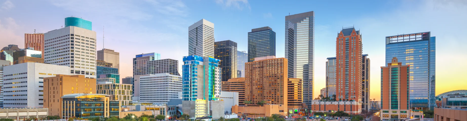 Houston, TX downtown skyline with city park and modern office buildings at sunrise.