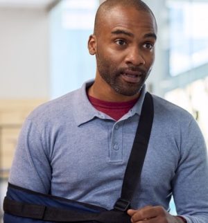 Employee with an injured arm discussing paperwork with a representative, illustrating the importance of disability insurance for employees.