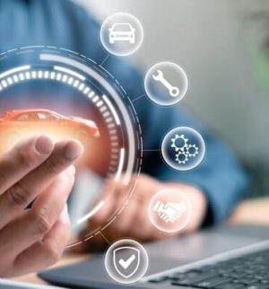 A man in front of a computer holding a toy car symbolizing the future of auto insurance with InsureOne.