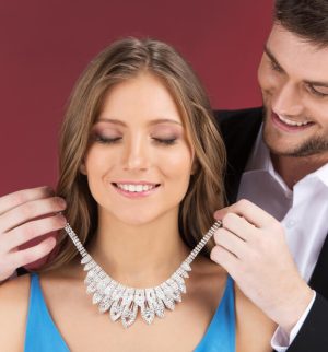 Man puts expensive diamond necklace on woman.