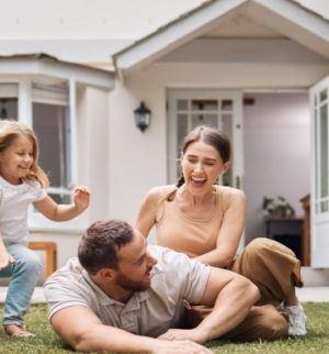 Happy family playing in front of their house - How Your Home's Age and Location Affect Your Insurance Rates - InsureOne