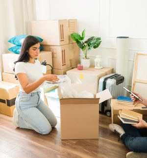 Couple unpacking moving boxes illustrating factors that can affect renters insurance rates.