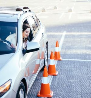 Student driver practicing around traffic cones to learn if driving school can lower car insurance.