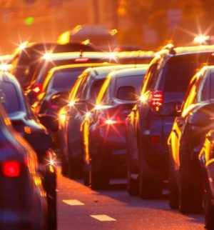 The morning rush hour is captured in this city street photograph, showing a line of cars amidst the hustle and bustle of the city and how your commute impacts your car insurance.