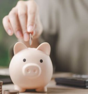 Woman adds a coin to a piggy bank, planning to save with multi-policy discounts.