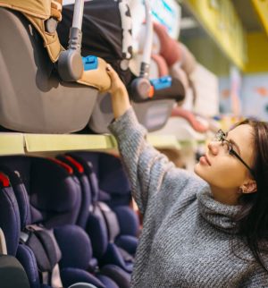 Pregnant woman choosing child car seat in store