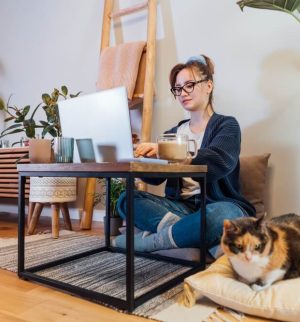 Remote professional working from a home office with a laptop and pet, illustrating the business insurance needs of remote work, including home-based business protection and equipment coverage.