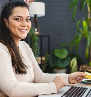 Woman using a laptop and holding a credit card, highlighting more insurance choices for credit union members.